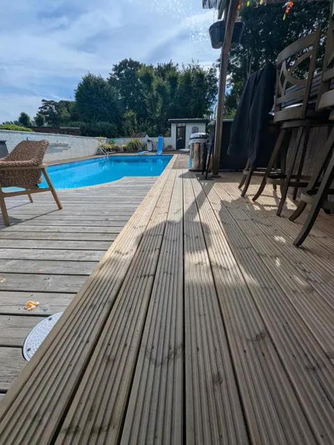 New grooved decking platform running alongside the swimming pool and existing deck in Ayr
