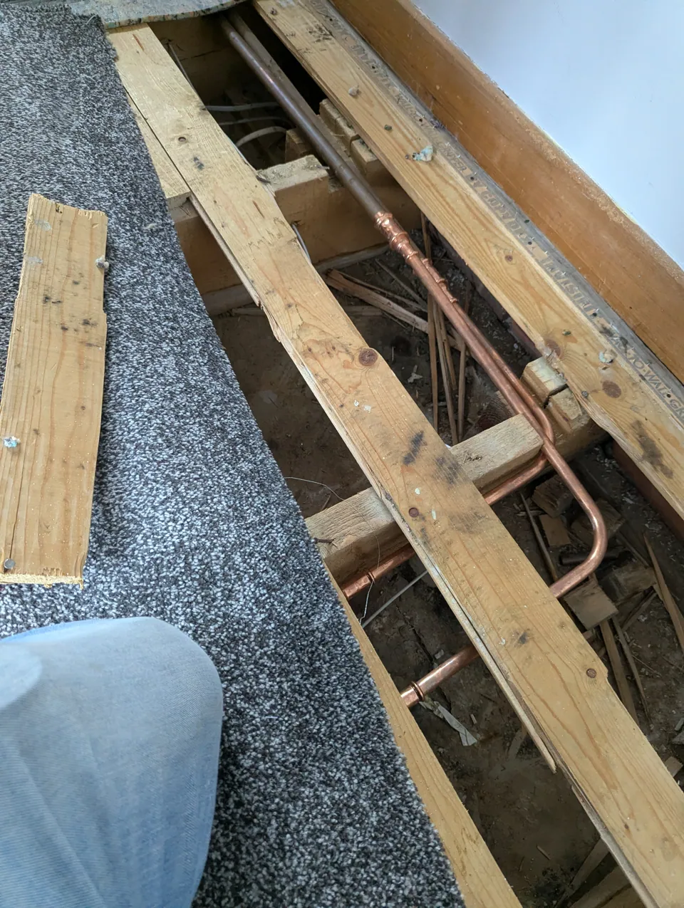 Floorboards lifted at a home in Irvine to give access to copper pipework under the floor after a burst pipe