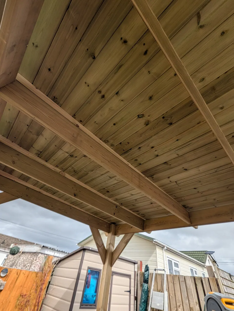 Underside of the boarded canopy roof showing the beams and the braced post below