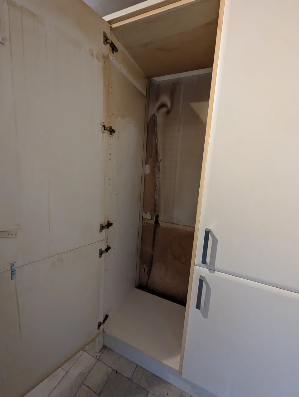 The housing with the old appliance removed, showing the aperture and the damage behind it before the replacement went in