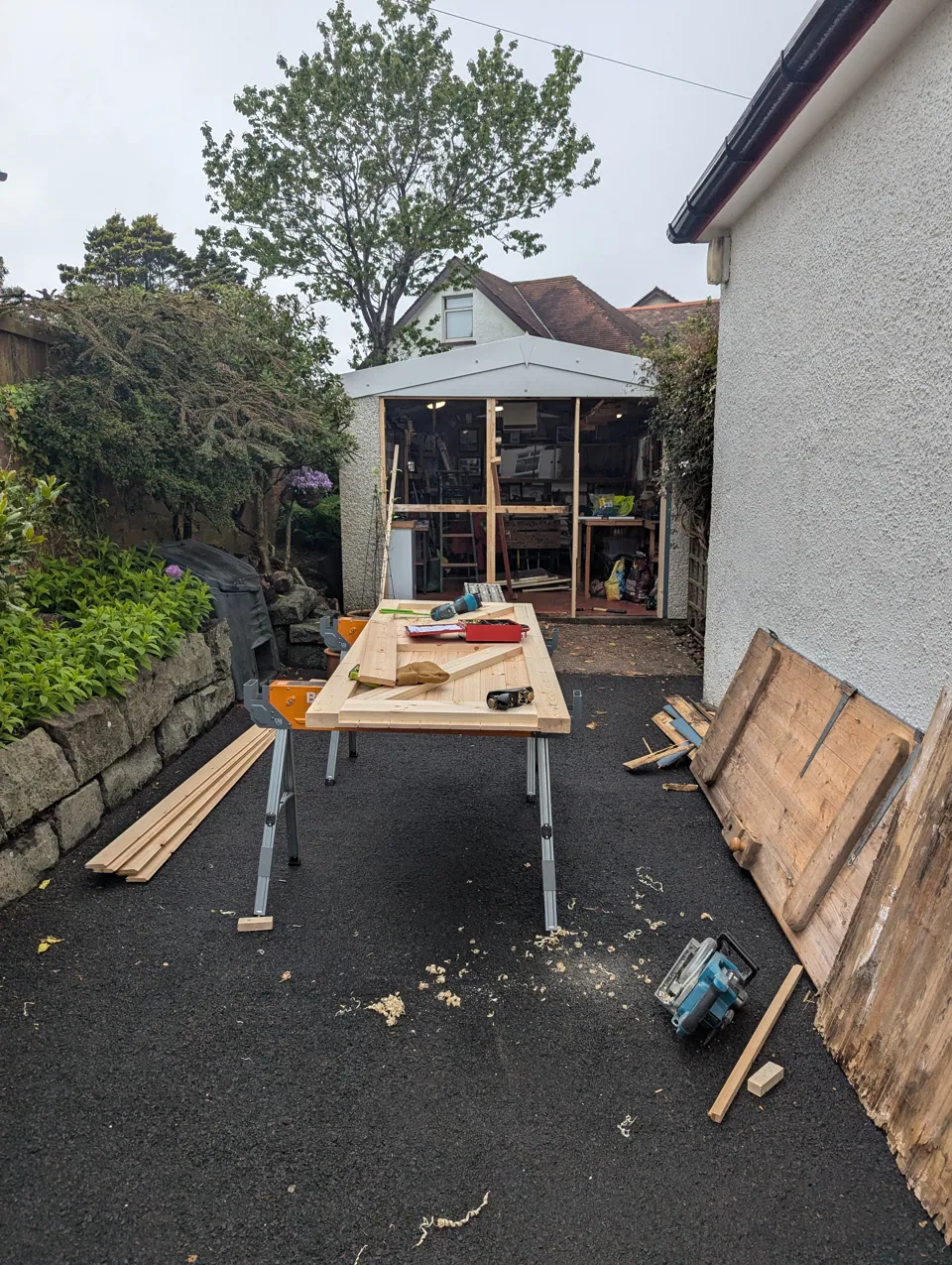The new ledged and braced door on trestles on site, with the old split and weathered door leaning against the wall behind