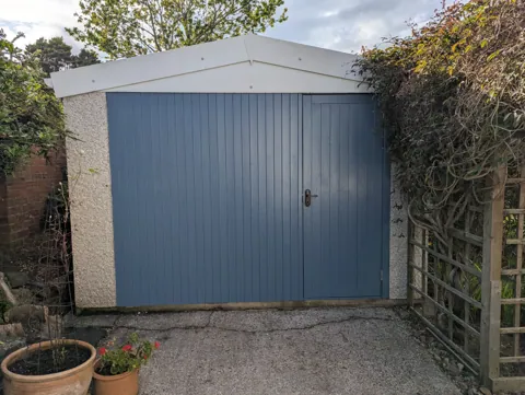 Finished garage front in West Kilbride, clad in channel lining and painted blue, with the ledged and braced door on the right