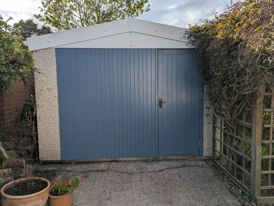 Finished garage front in West Kilbride, clad in channel lining and painted blue, with the ledged and braced door on the right
