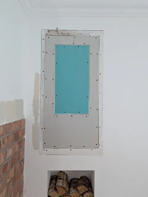 Plasterboard-faced access hatch framed and fitted into the wall beside a chimney breast in Irvine, ready for the plasterer to skim