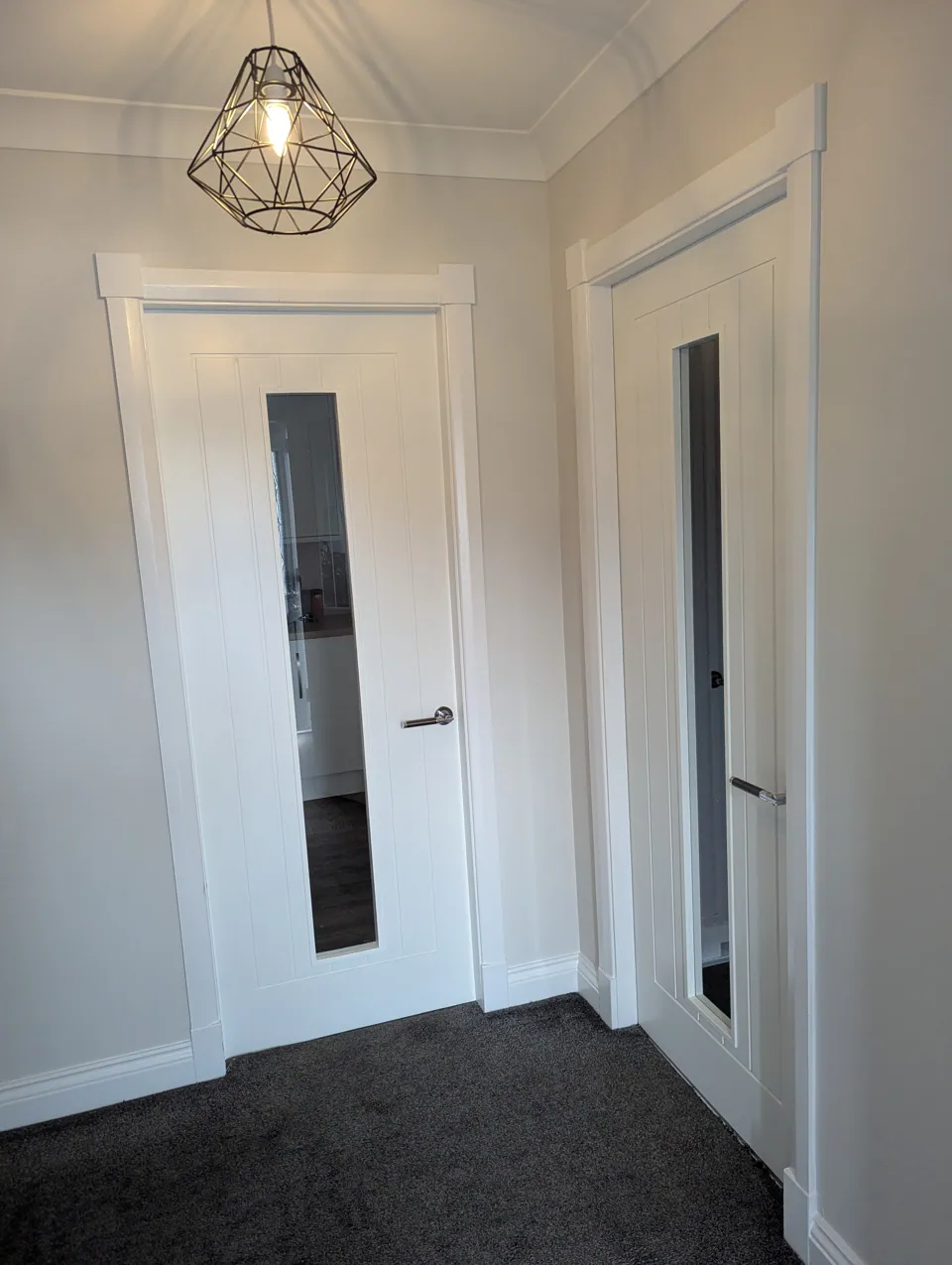 Two glazed white internal doors fitted off a hallway in Irvine, lit by a pendant light