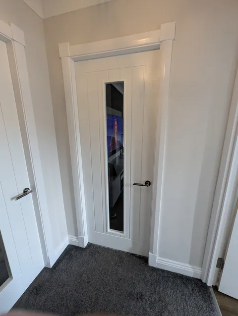 Premium white glazed internal door fitted in an Irvine home, with chrome lever handle and moulded head detail above the opening