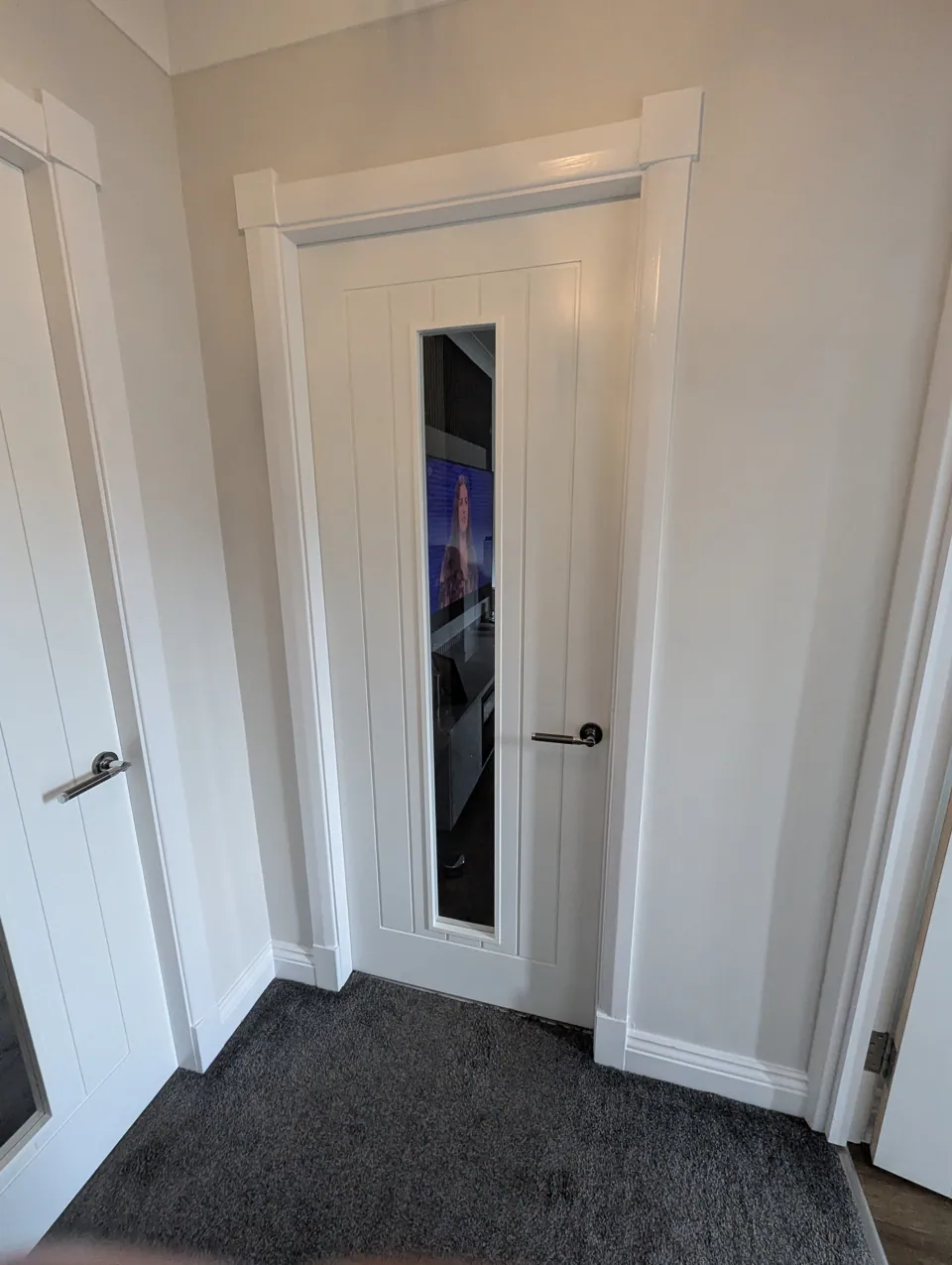 Premium white glazed internal door fitted in an Irvine home, with chrome lever handle and moulded head detail above the opening