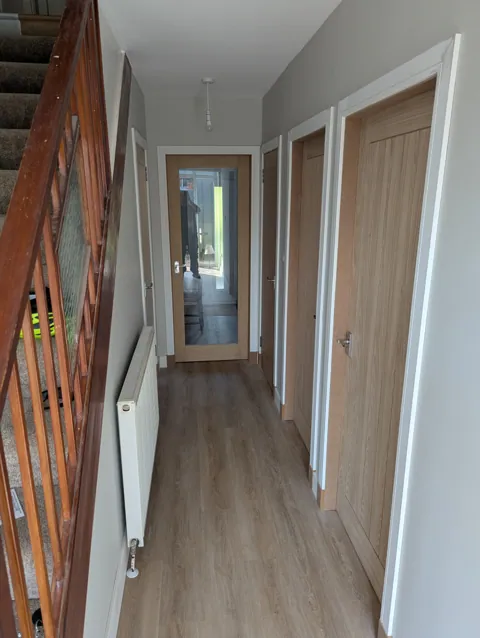 Downstairs hall in Irvine with new oak veneered doors, white facings and skirting and a fully glazed oak door at the end