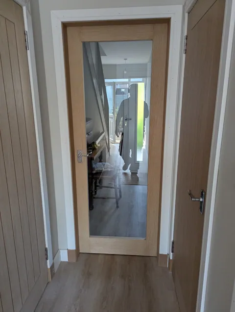 Fully glazed shaker style oak door with chrome scroll handle fitted in an Irvine hallway