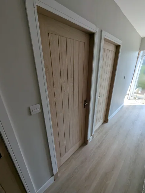 Two oak cottage style doors with new white facings and skirting in an Irvine hallway
