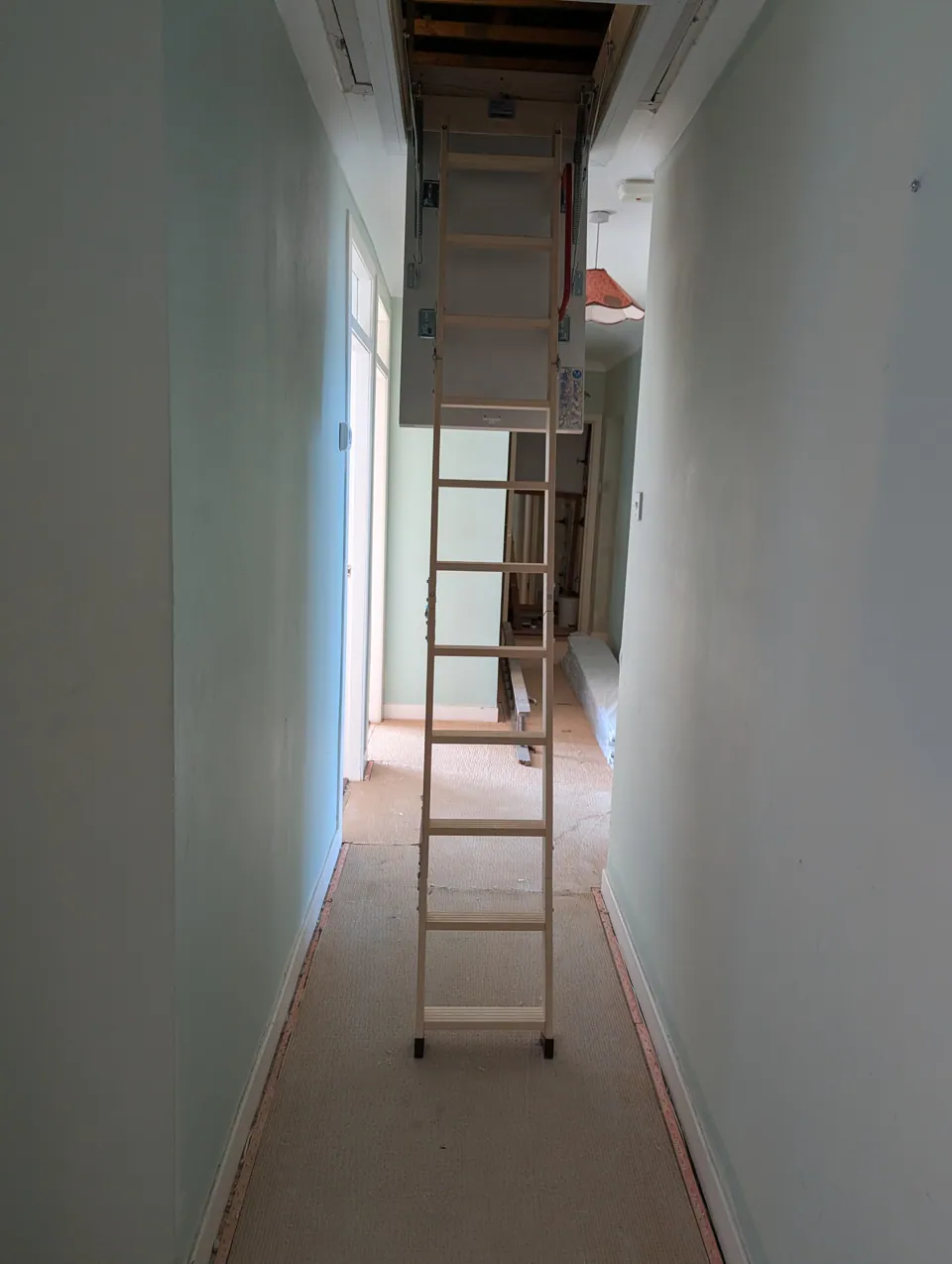 Folding timber loft ladder extended down into a hallway in Largs from the new loft hatch