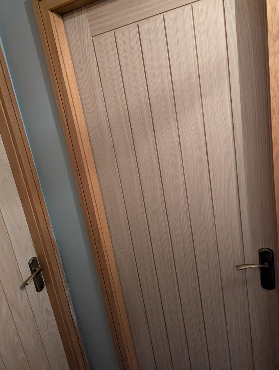 Two oak veneered doors on the same landing with matching antique brass handles