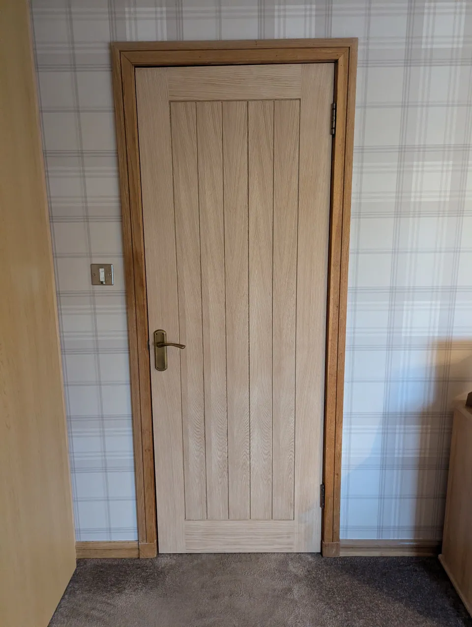 Oak veneered internal door hung in a Lugton bedroom, with antique brass lever handle and oak facings
