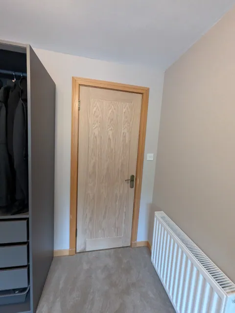 Oak veneered internal door hung beside fitted wardrobes in a Lugton bedroom