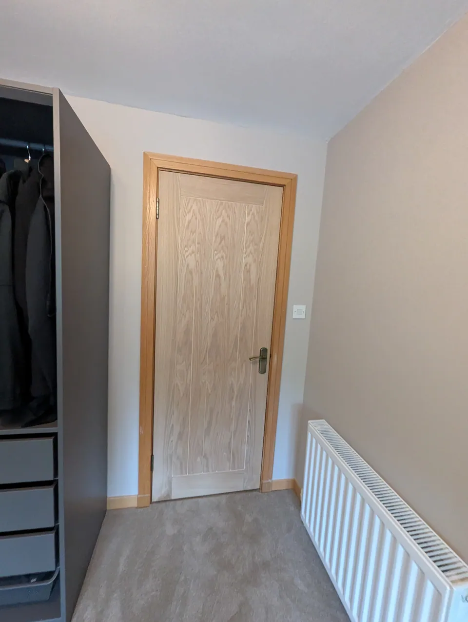Oak veneered internal door hung beside fitted wardrobes in a Lugton bedroom