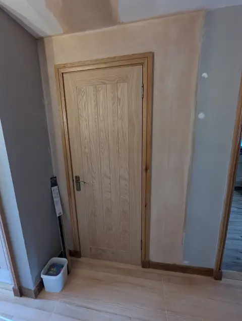 Oak veneer cottage door fitted in a Lugton hallway with oak frame and antique brass handle