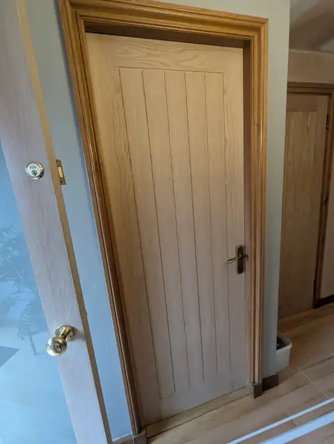 Oak veneer cottage door in the downstairs hall with antique brass lever handle