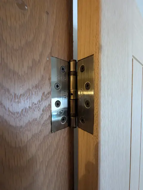 Close-up of an antique brass butt hinge fitted to an oak veneer door