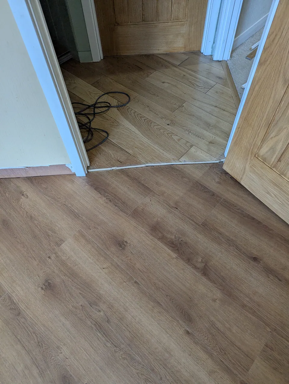 New flooring meeting existing oak flooring at a doorway, cut in around the linings