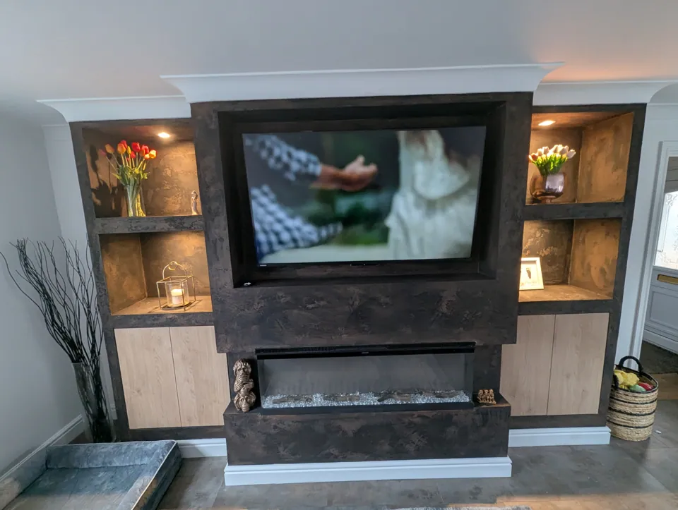 Full-width bespoke media wall in an Irvine living room with recessed TV, electric fire, lit alcoves and cabinets, finished in Venetian plaster