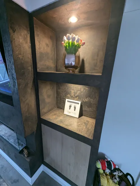 Close-up of a lit display alcove and cabinet, showing the depth and movement in the Venetian plaster finish