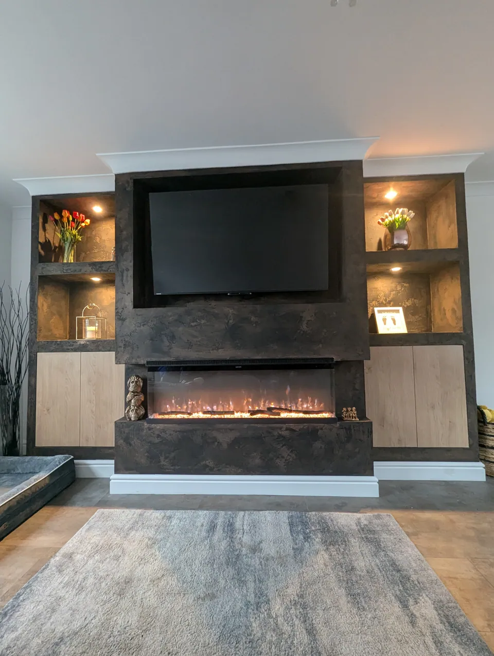 Media wall with the electric fire lit, showing the Venetian plaster finish and lit display alcoves