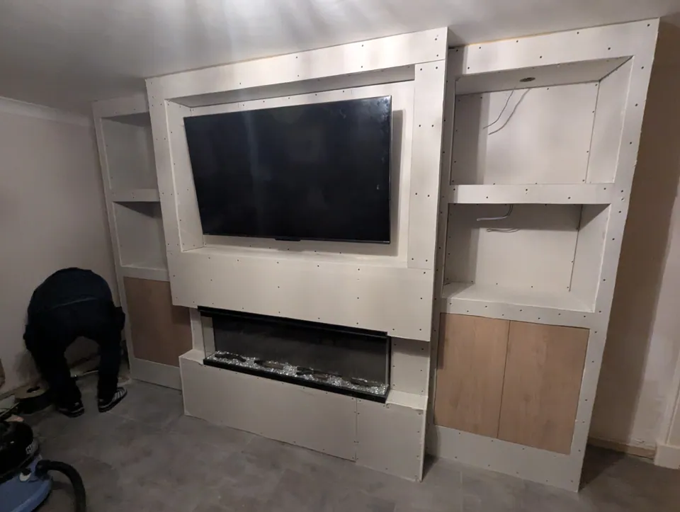The media wall boarded out during construction, with the TV recess and fire aperture formed and the cabinets going in, before plastering