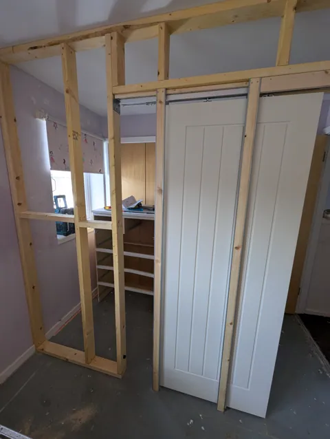 Timber stud partition framed with a pocket door kit and the sliding door hung on its track, Irvine