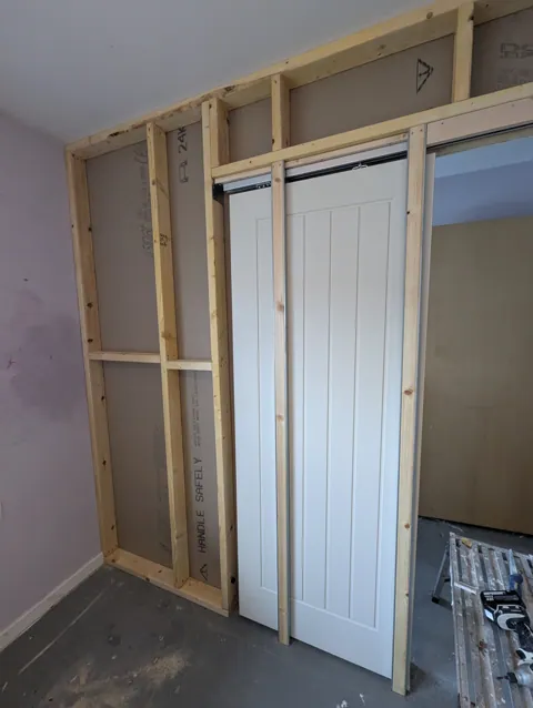Stud partition boarded on one side with the pocket door cassette and sliding door visible, Irvine