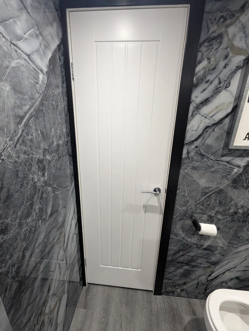 White cottage style internal door fitted in a Prestwick bathroom against dark marble-effect walls, with chrome lever handle