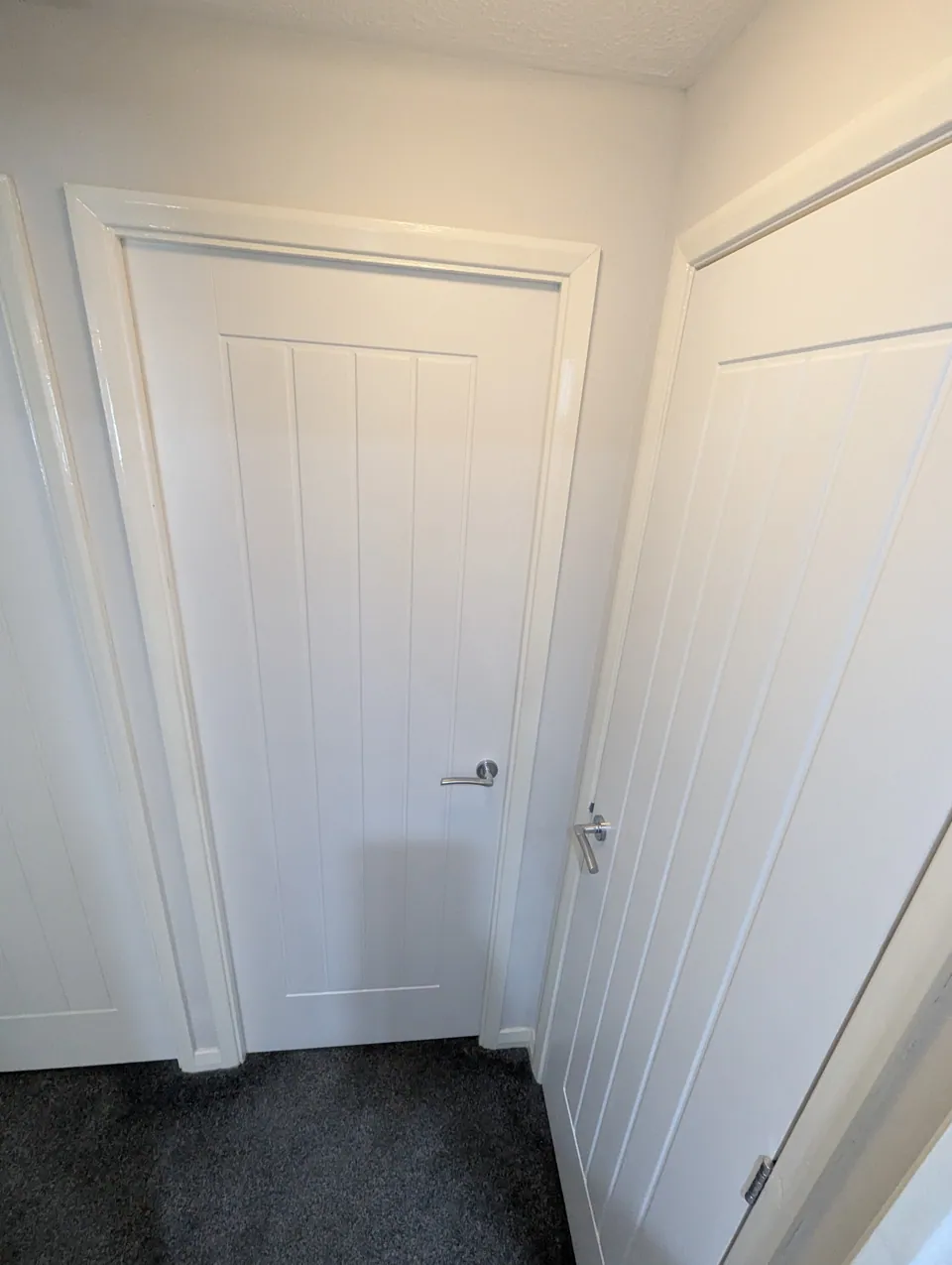 Two white cottage style internal doors with chrome lever handles set at matching heights