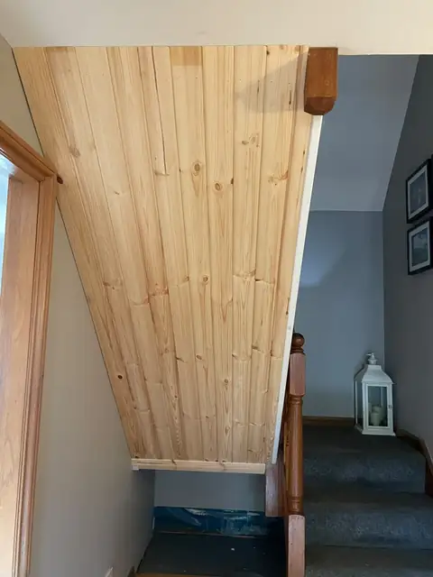 V-grooved timber lining fitted to the underside of a staircase in a Lugton hallway, ready for decoration