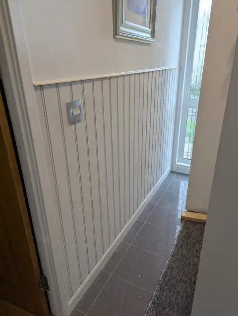 Grain-embossed tongue and groove panelling fitted at half height along a hallway in Irvine, with a capping rail, ready for painting
