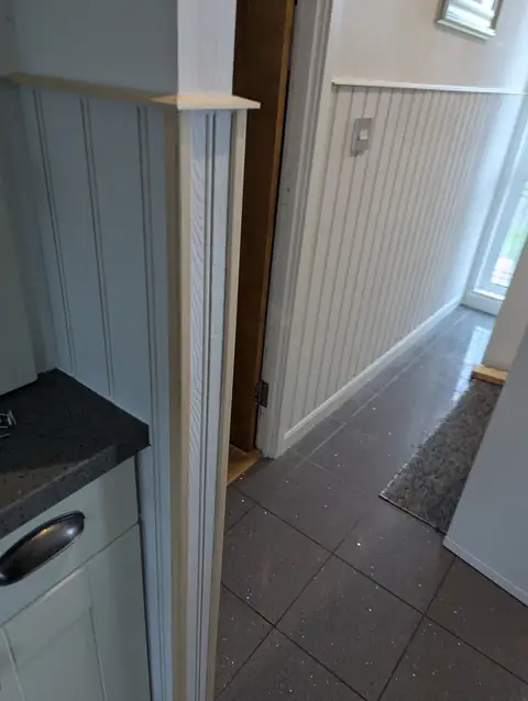 Panelled pier at the kitchen entrance with the panelled hallway beyond, on a tiled floor in Irvine