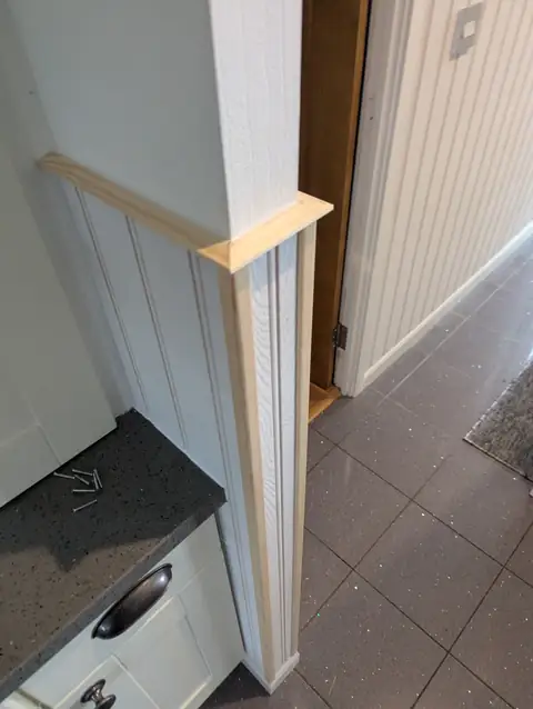 Timber capping rail mitred around the corner of a panelled kitchen pier