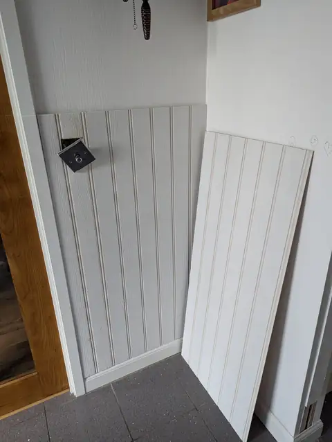 First pre-primed tongue and groove boards fixed to a laser line beside a glazed oak door, with the next board ready